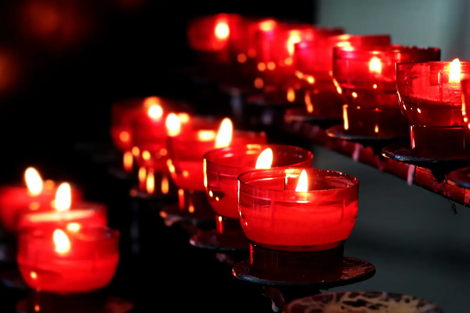 Rows of red votive candles glowing in darkness