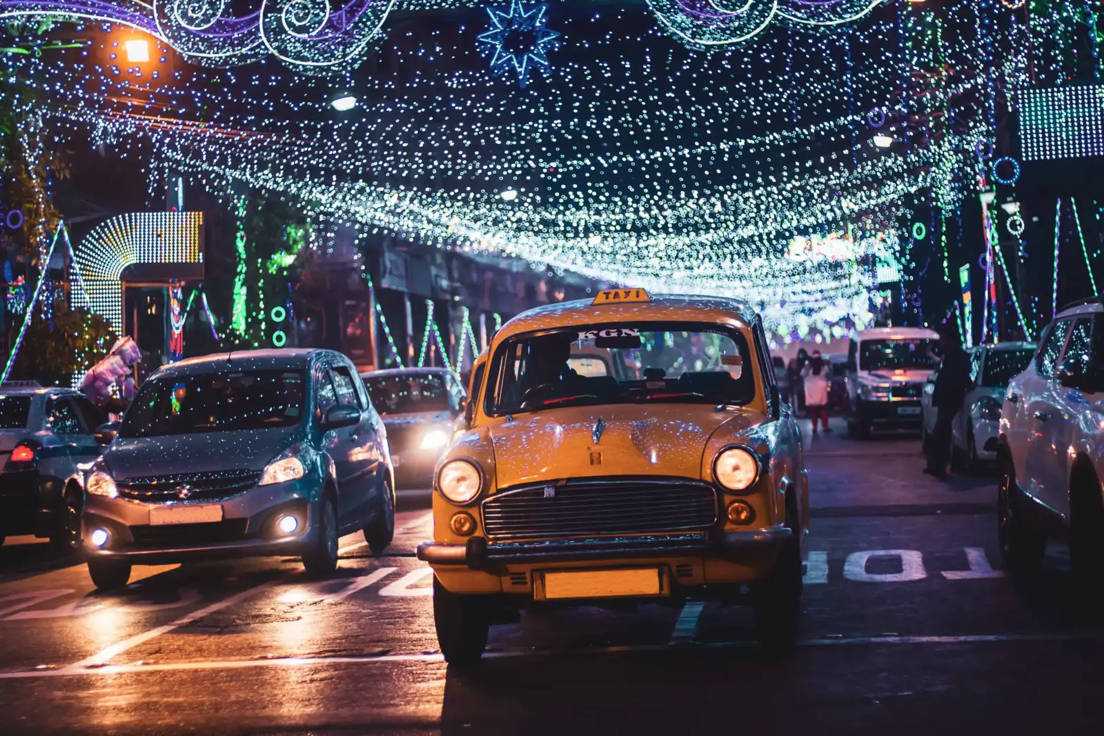 Vintage yellow taxis under a canopy of festival lights at night