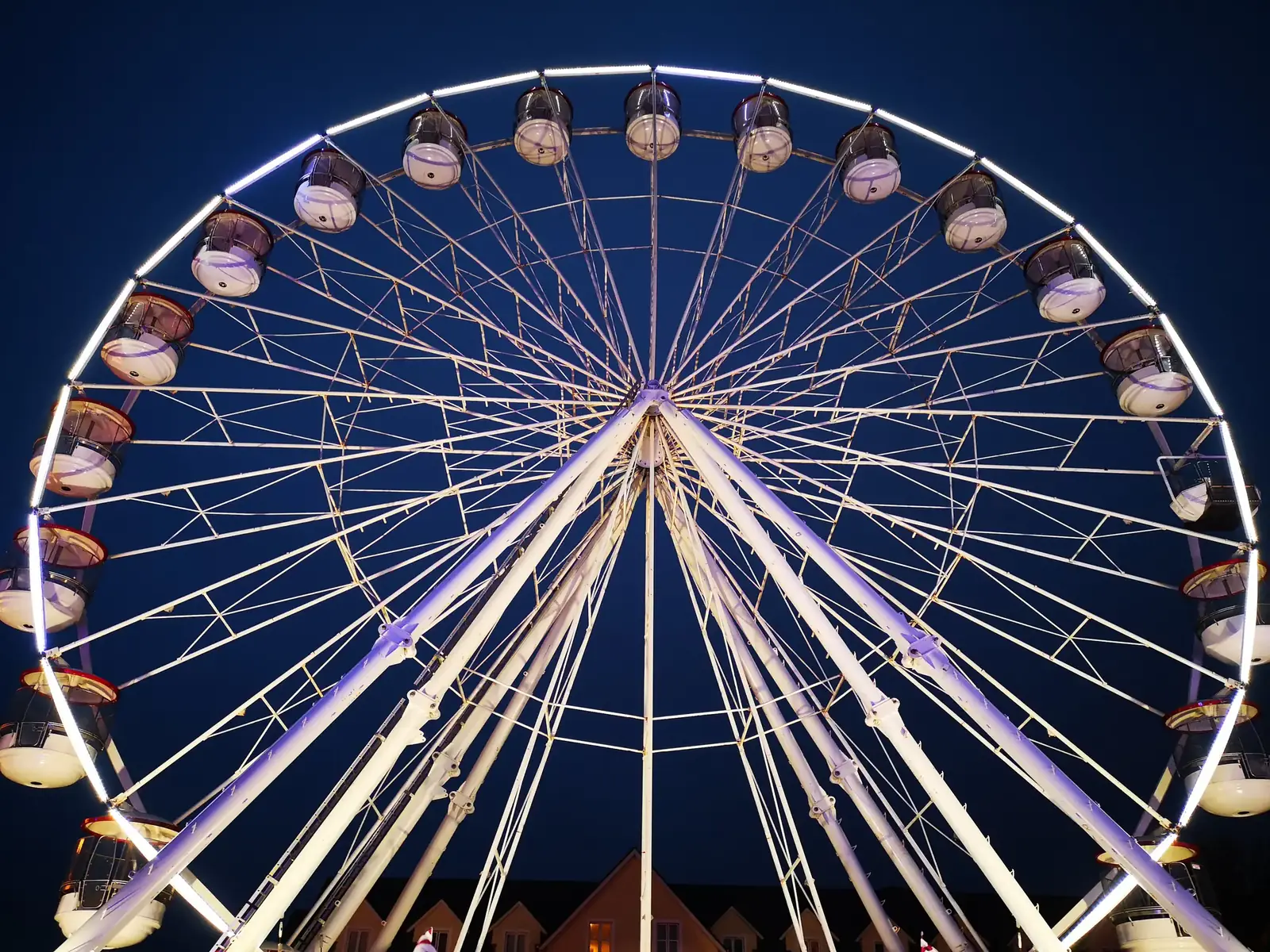 A ferris wheel lit up against a deep blue night sky