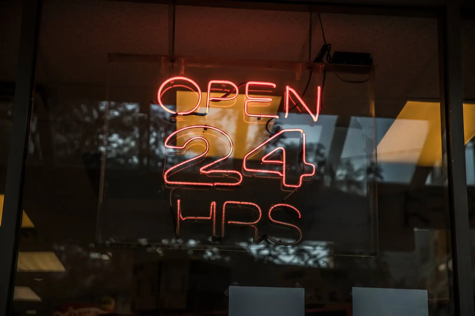 A red "Open 24 hrs" neon sign in a window
