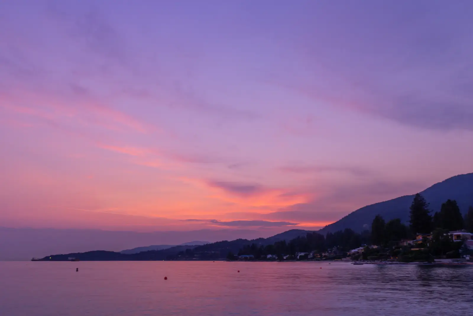 A purple and pink sunset reflected in calm coastal water