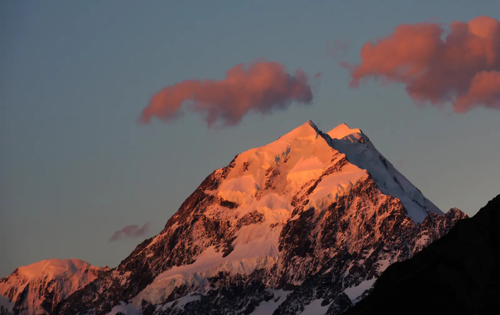 A snow peak lit pink by the last light, with pink clouds