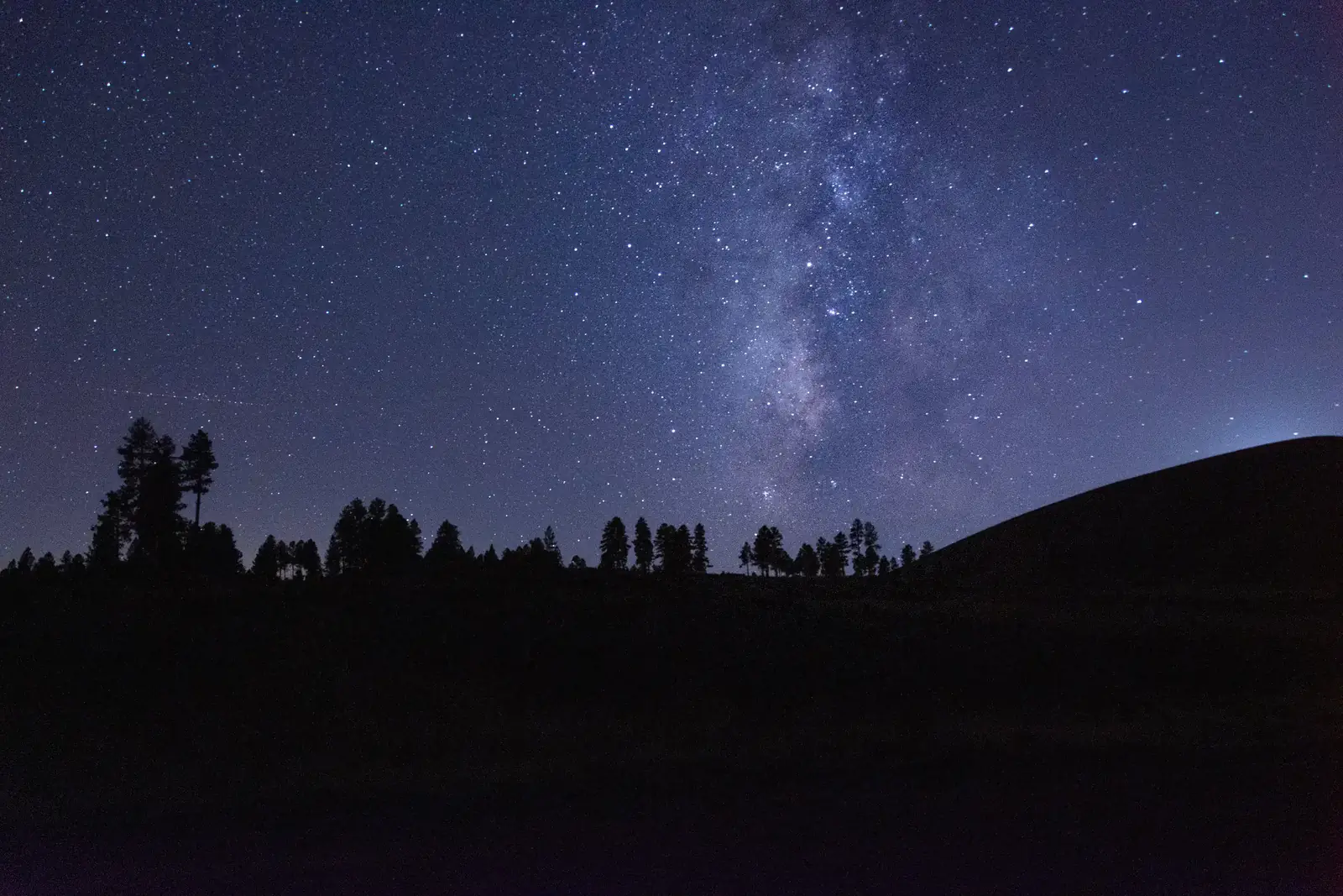 The Milky Way rising over dark hills