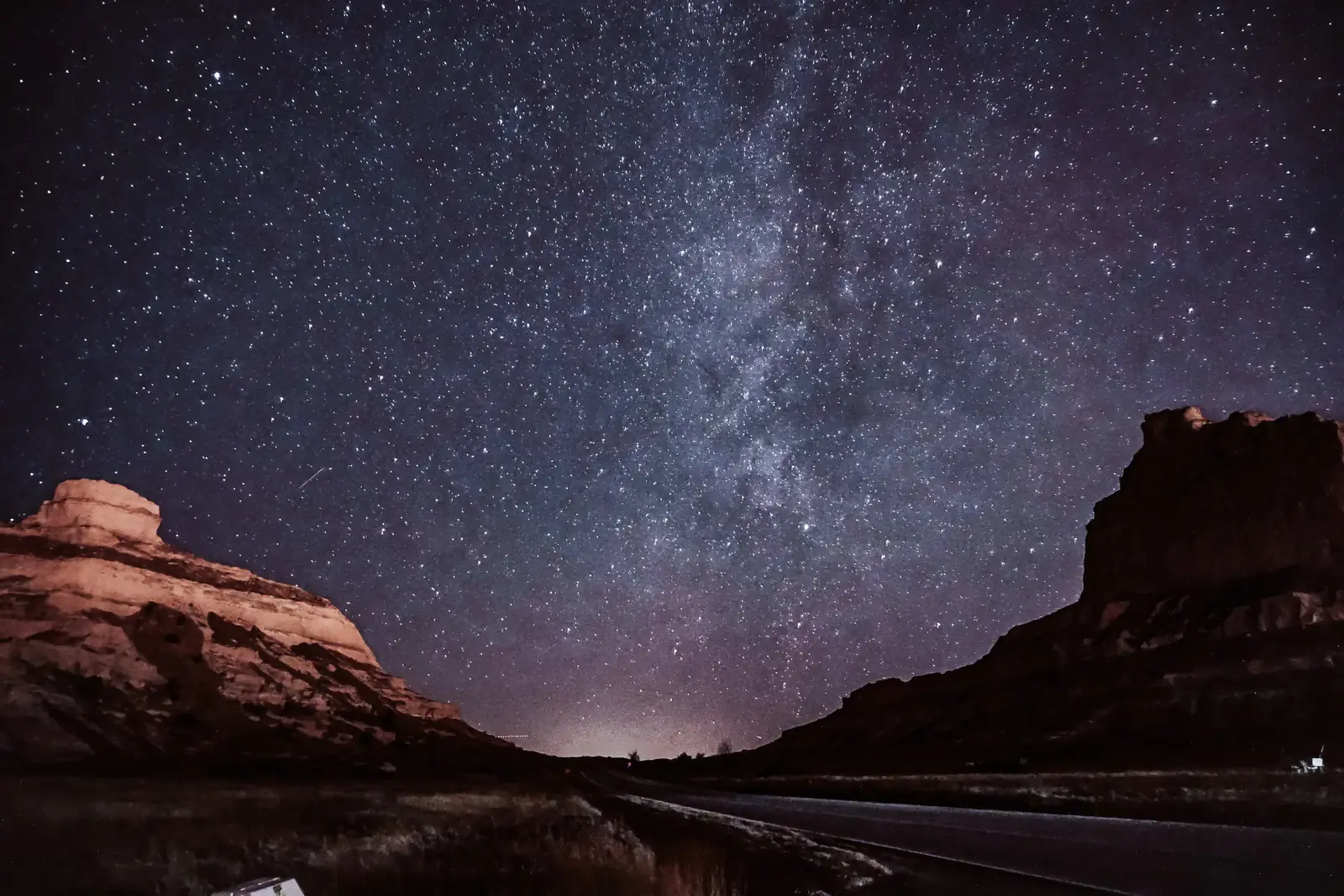 The Milky Way arching over red desert rocks