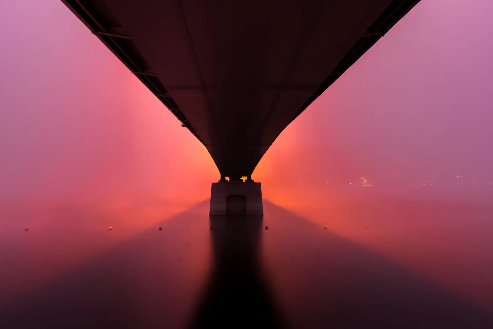 The underside of a bridge vanishing into hot-pink fog