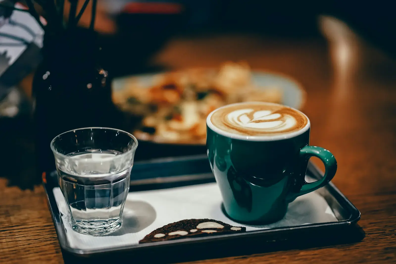 A glass of water and a latte on a tray in a café