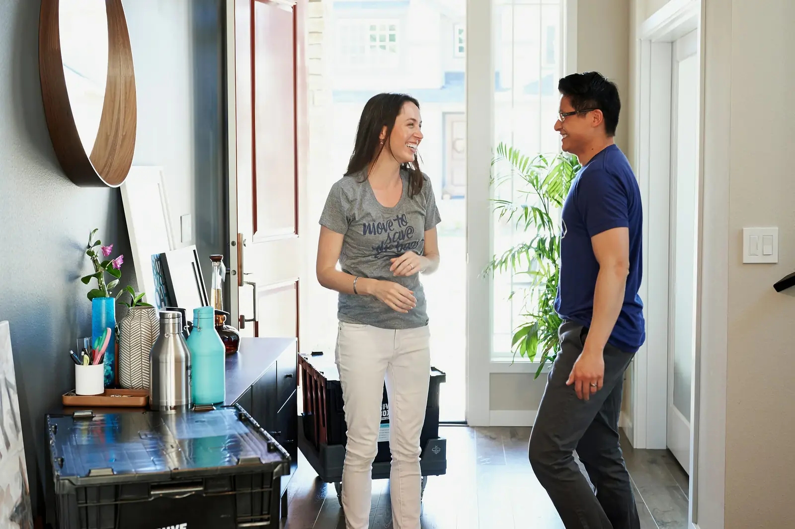 A woman and a man talk in a bright hallway by the front door