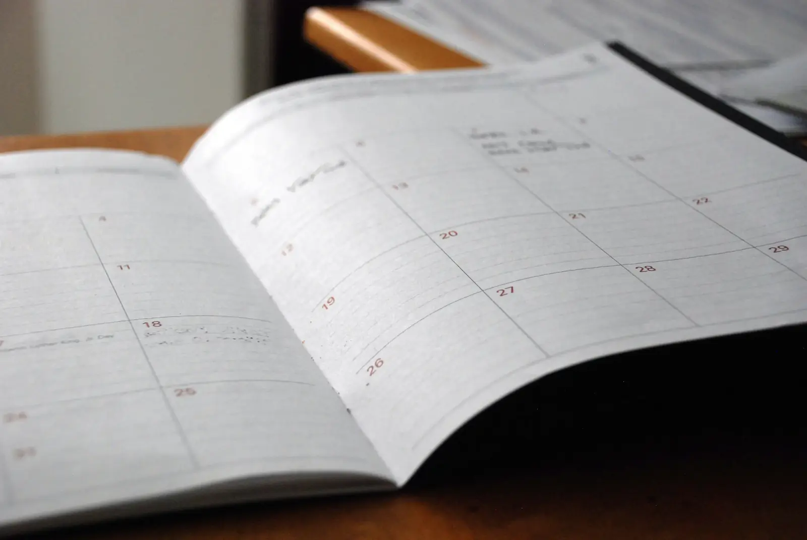 An open paper monthly planner on a desk in soft light