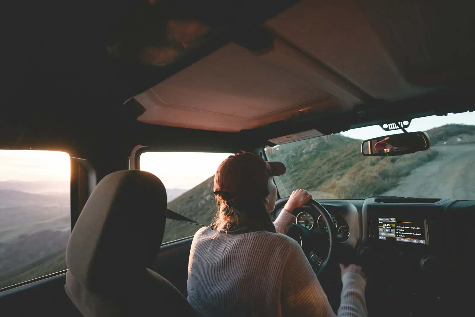 A woman drives on a country road while her passenger looks out the window