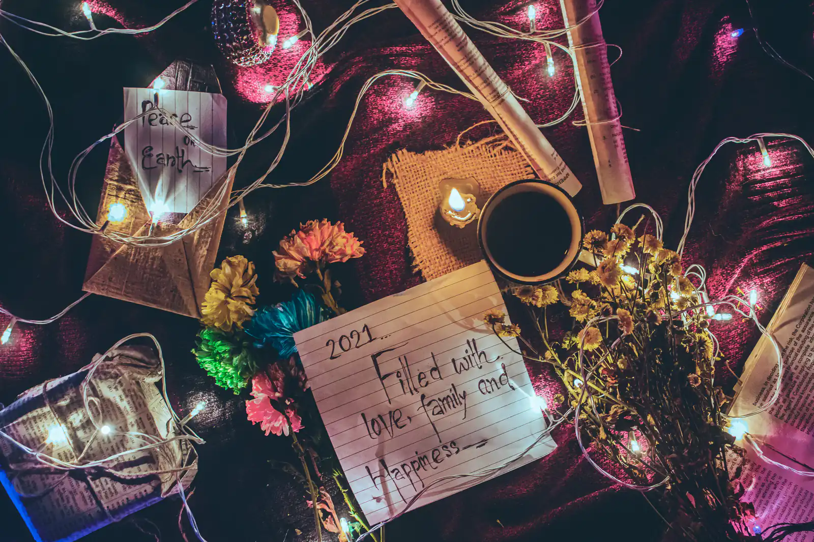 Handwritten letters, flowers and fairy lights on a dark table