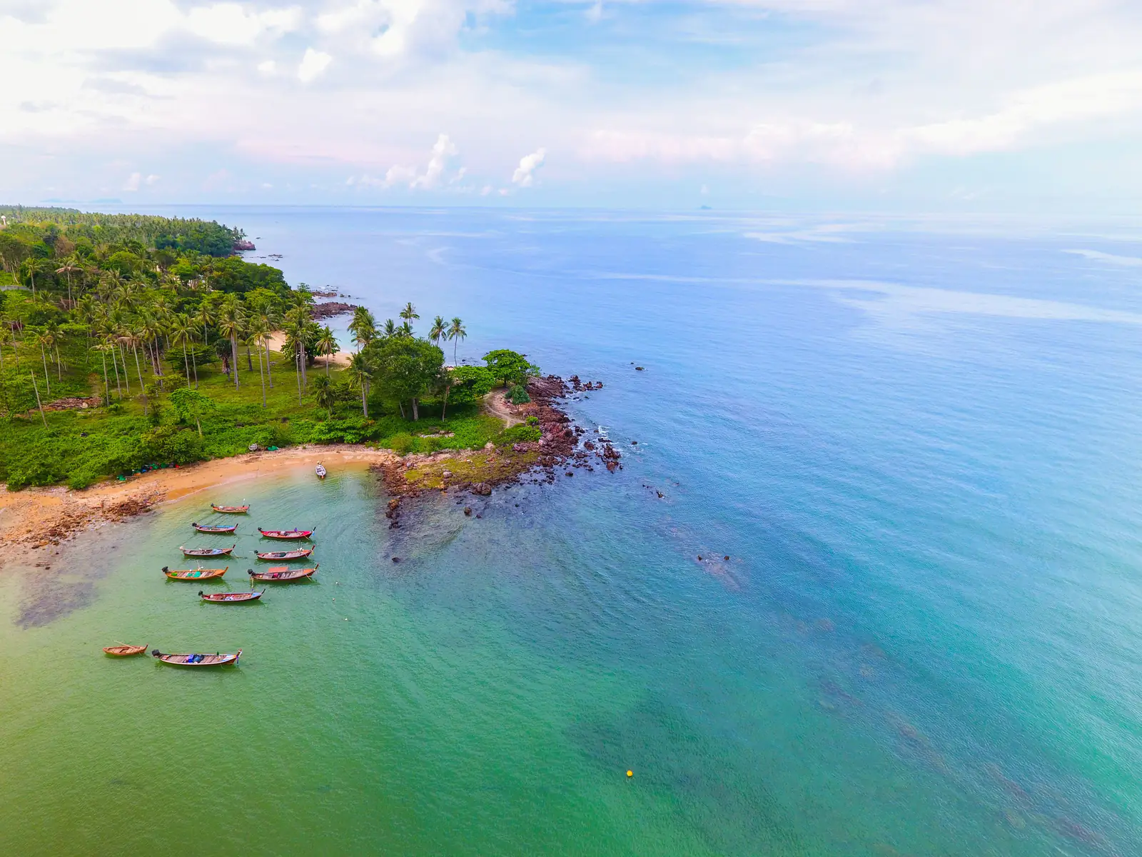 Canoes on a palm-fringed shore beside a turquoise bay