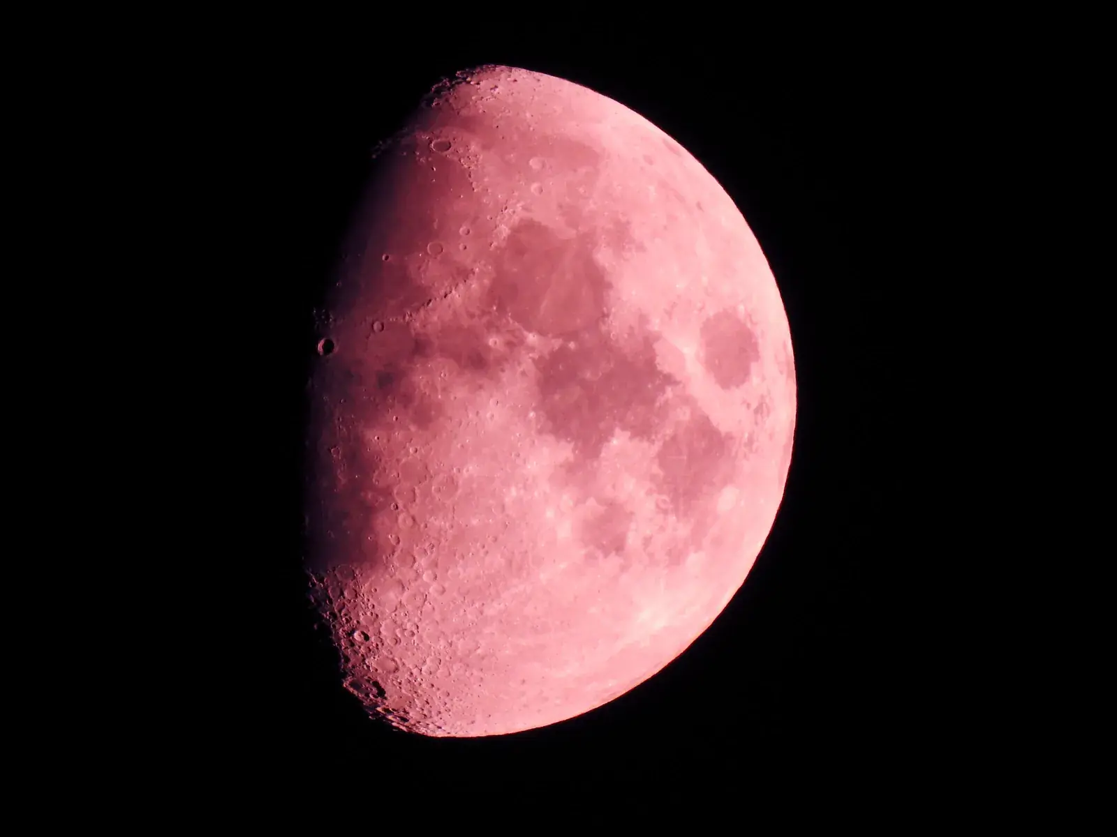 A waxing Moon tinted pink by the atmosphere
