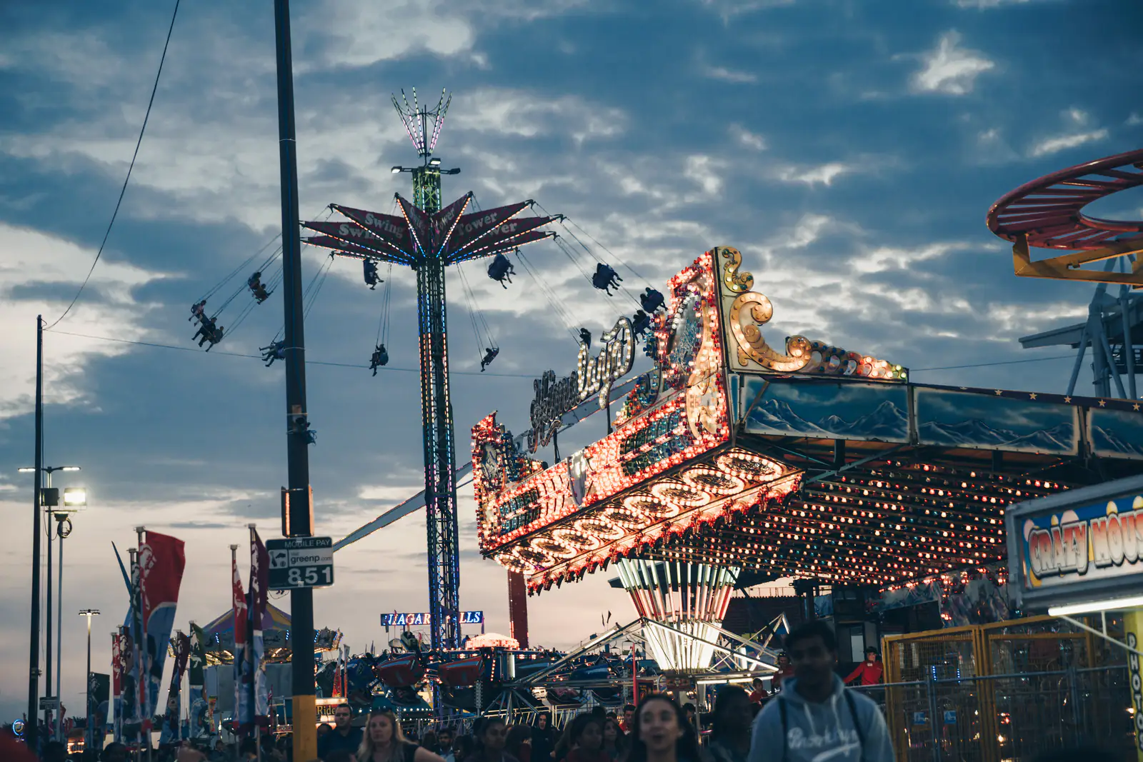 Fairground rides spinning against an evening sky