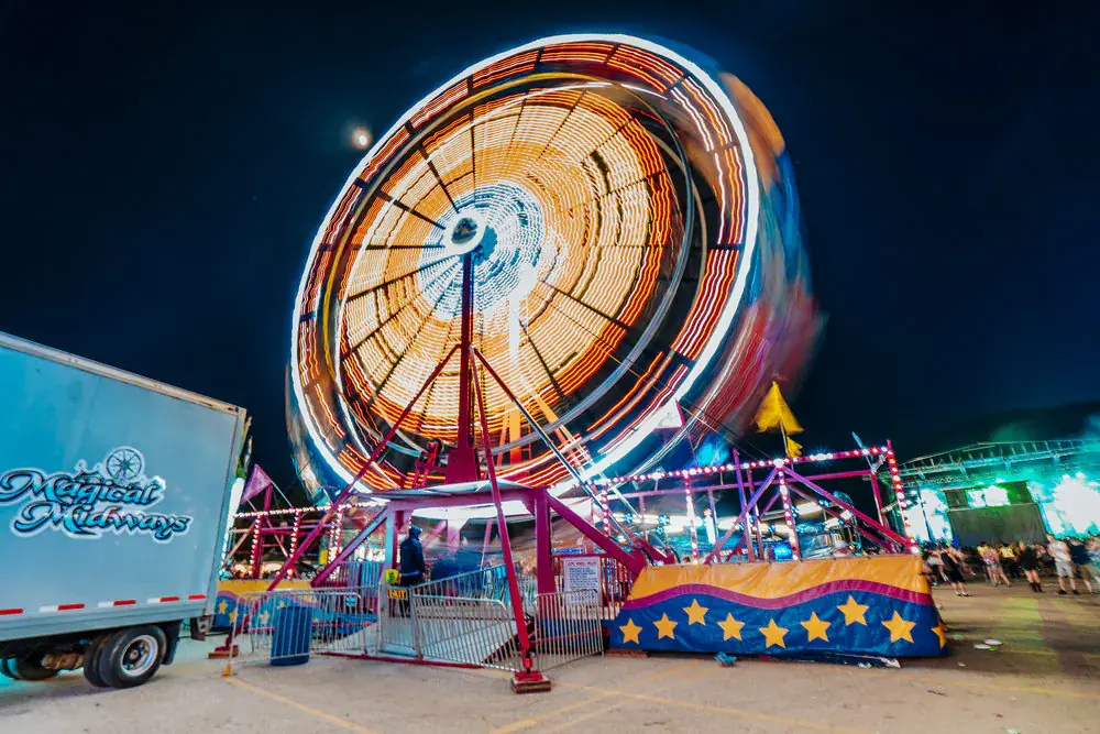 A ferris wheel spinning in a blur of orange light at a night fair
