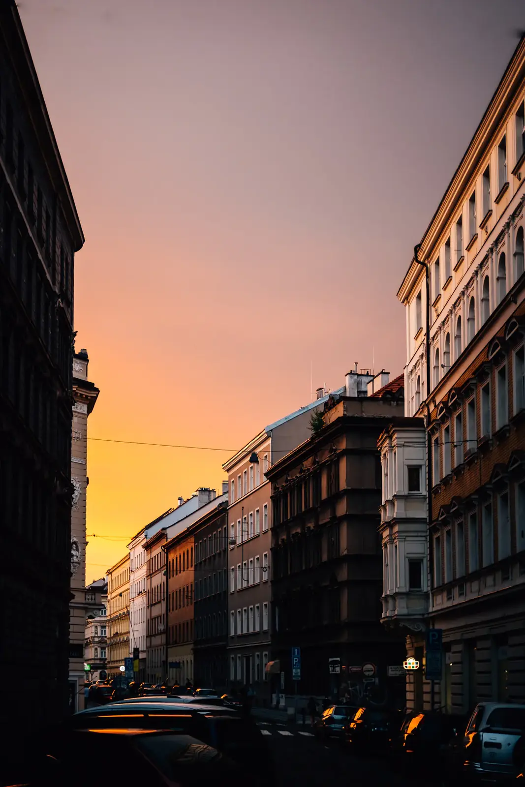 A city street glowing under a pink dusk sky