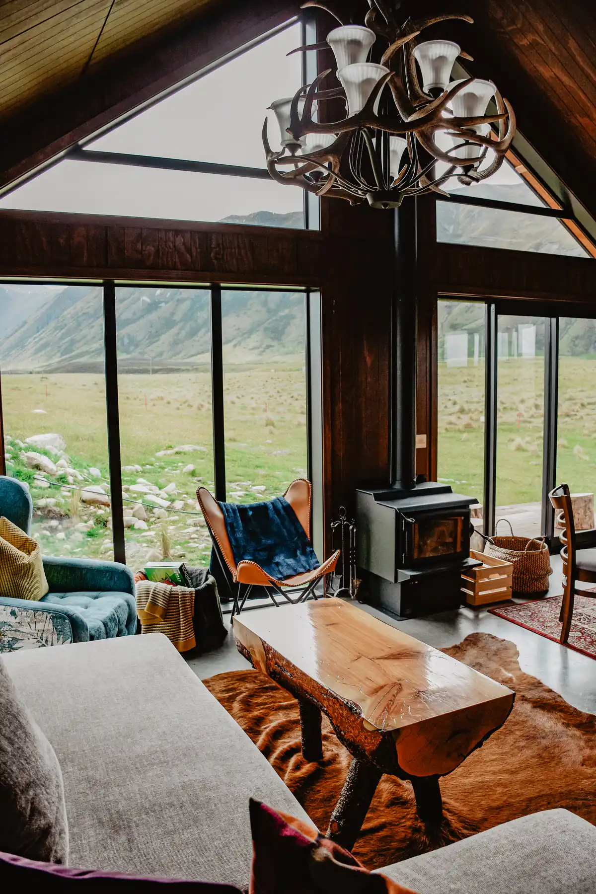 A warm cabin living room with a wood stove and big windows