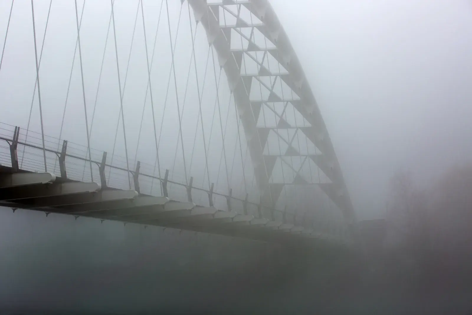 A bridge arching into dense fog
