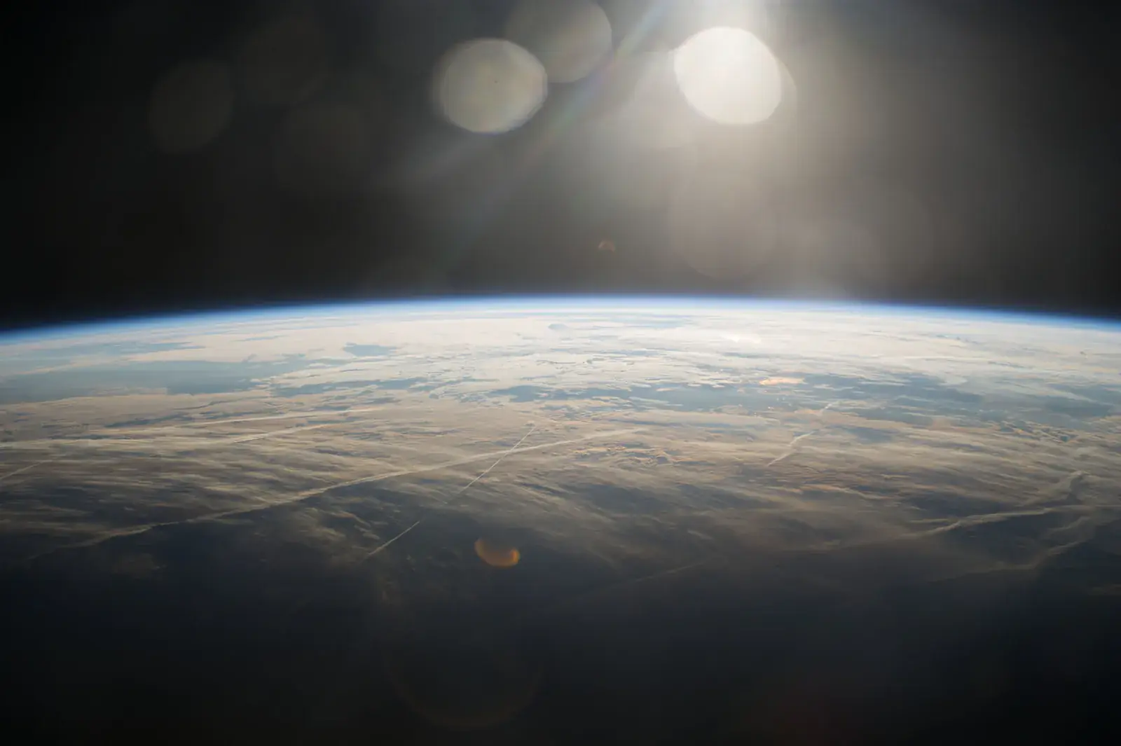 The Sun glowing over the curve of the Earth from orbit