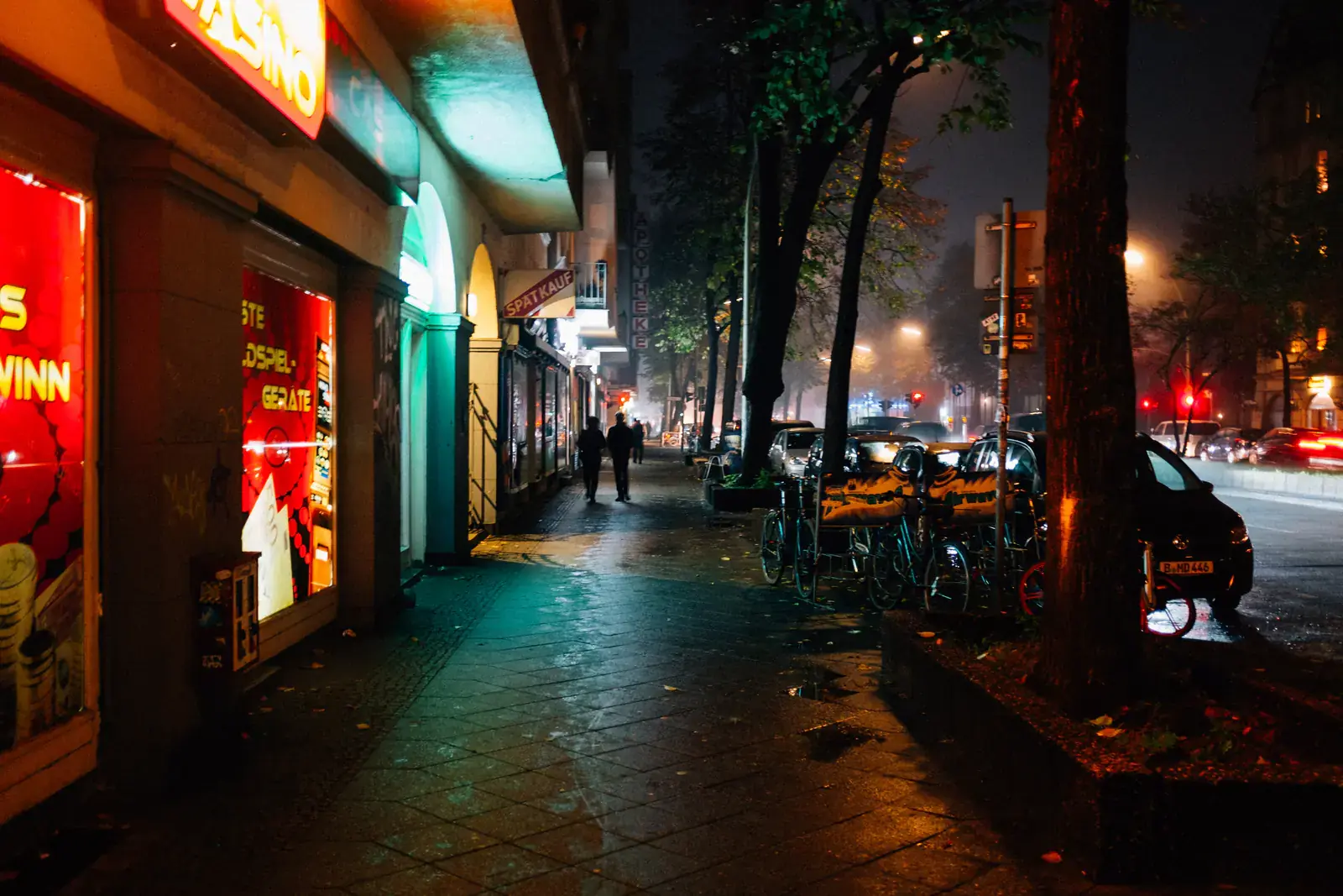 A wet city street at night lit by shopfront neon