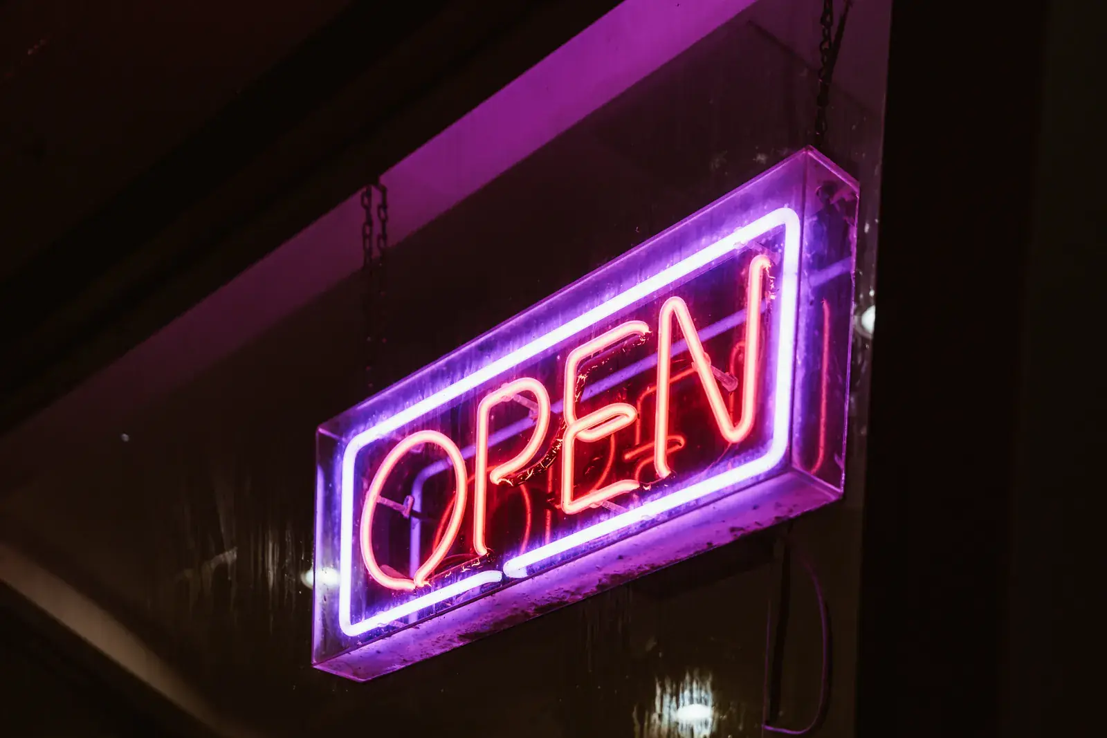 A purple OPEN neon sign glowing in a dark window