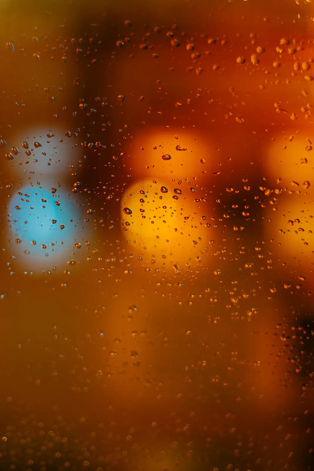 Orange and blue city lights through a rainy window