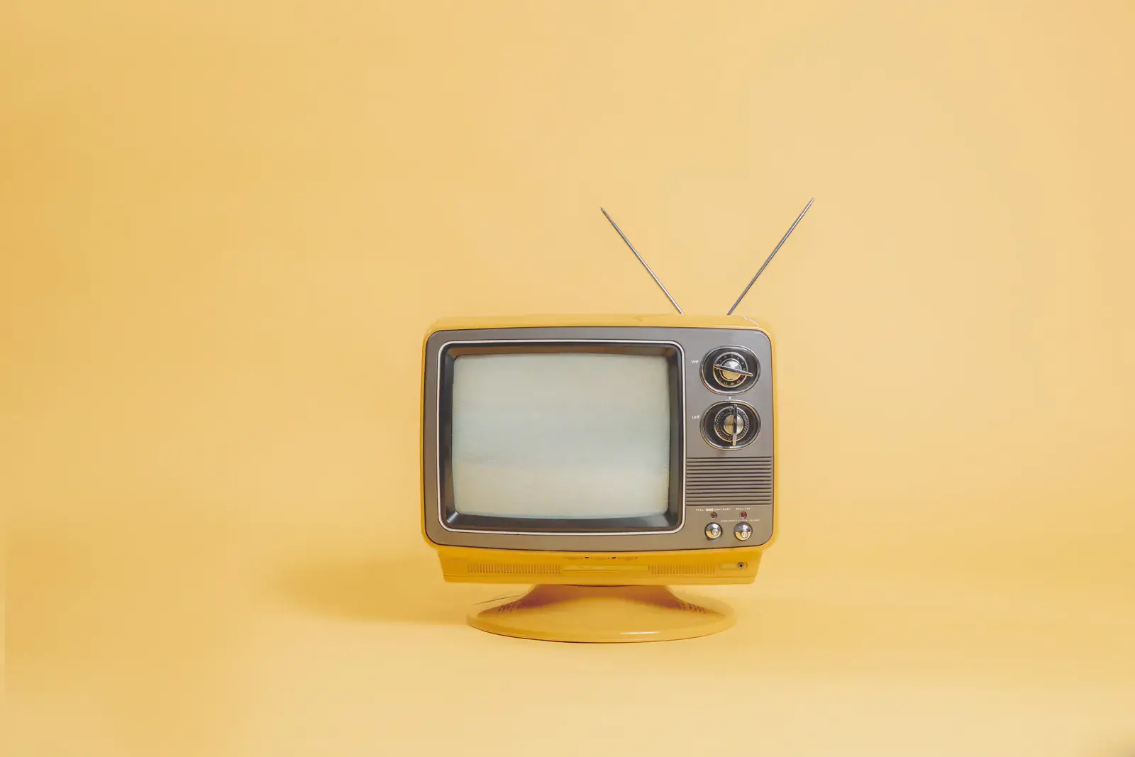 A small yellow vintage TV on a butter-yellow background