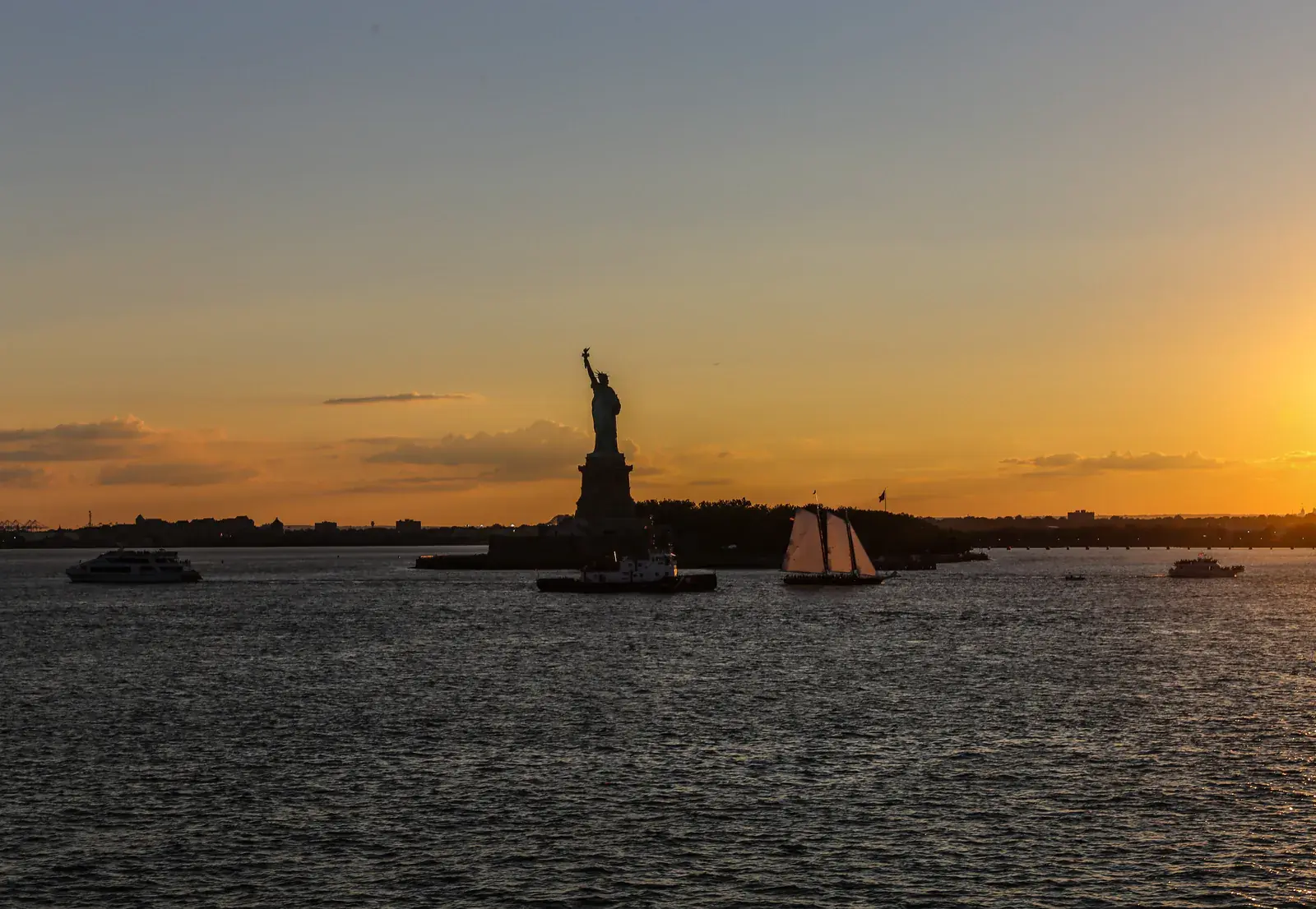 A harbour statue silhouetted against an orange sunset