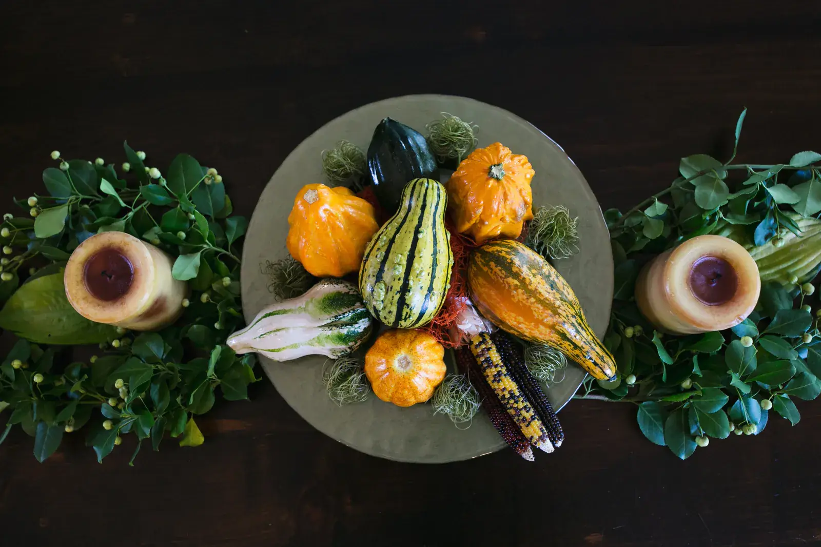 Gourds and squash on a dark platter among greenery