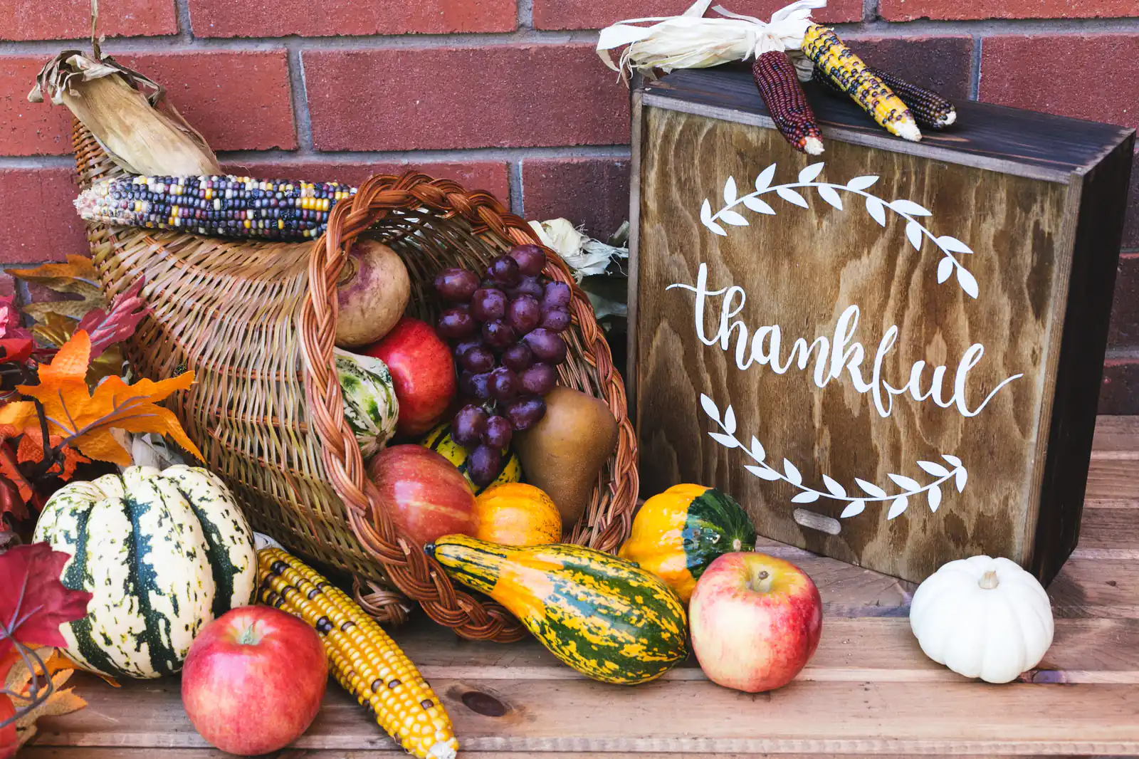 A harvest cornucopia of gourds and apples beside a "thankful" sign