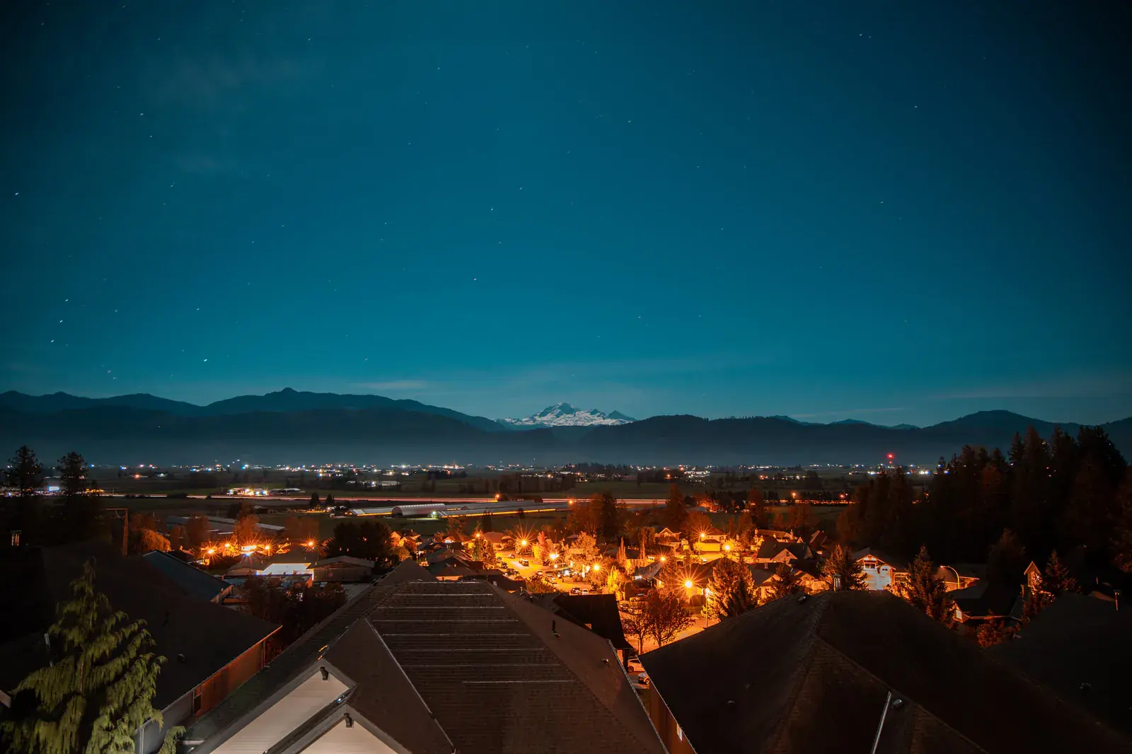 City lights at blue hour beneath distant mountains