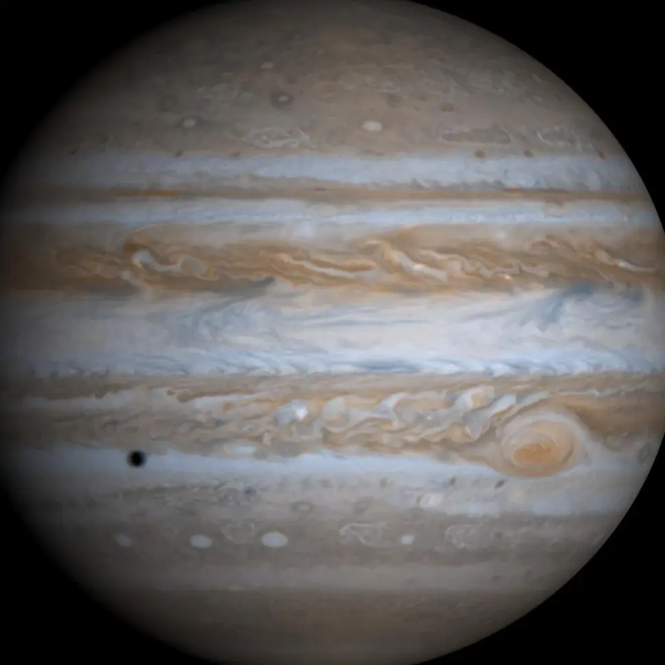 Jupiter's banded clouds and Great Red Spot, with the shadow of the moon Io, photographed by Cassini