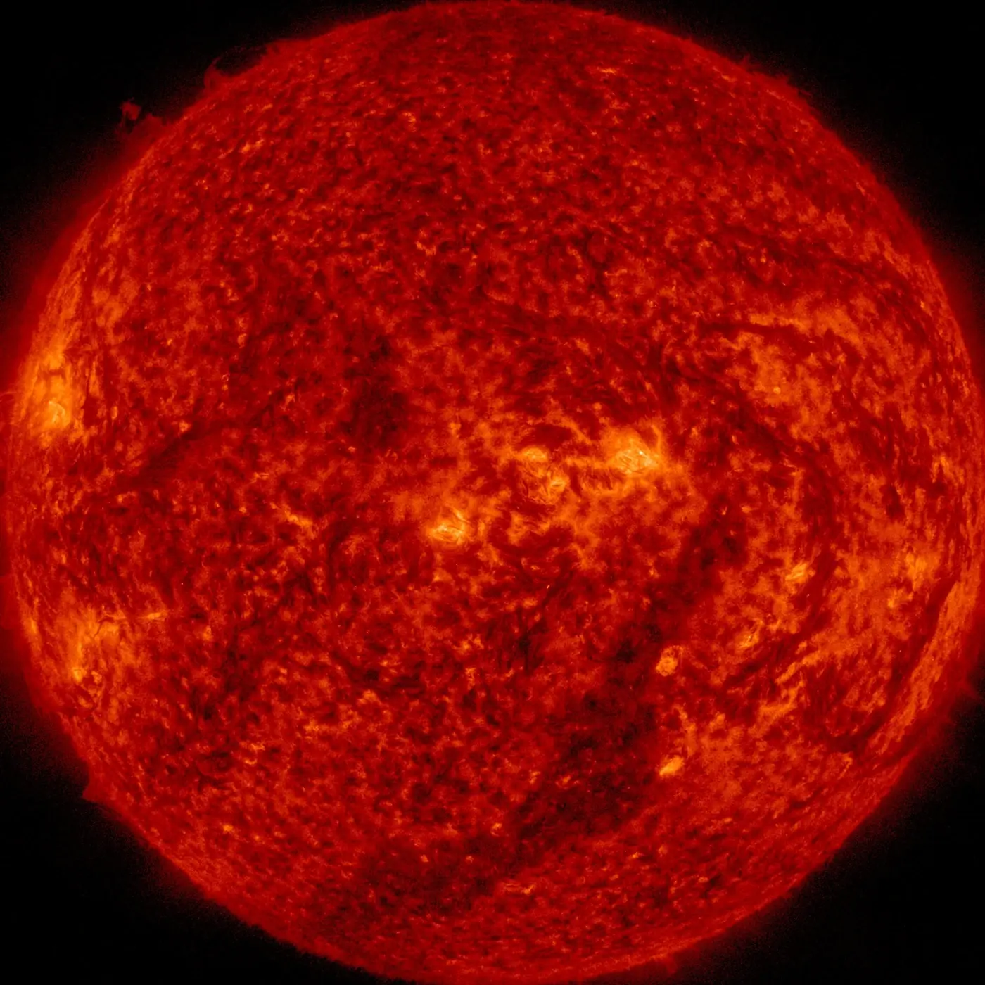 The Sun in extreme ultraviolet light at 304 angstroms, glowing red-orange with bright active regions