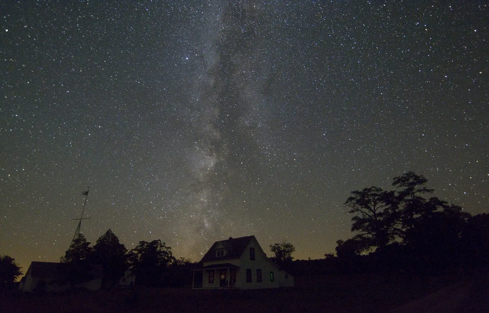 The Milky Way over a quiet island village and its trees
