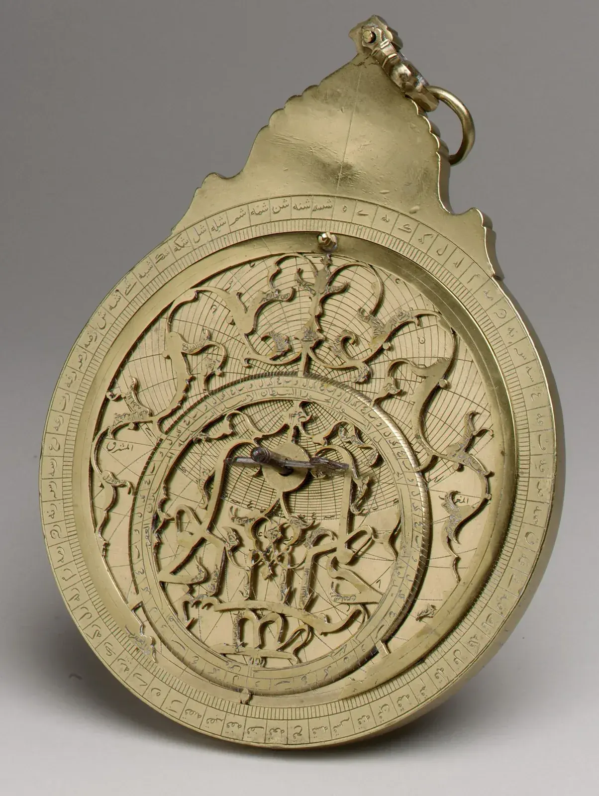 Brass astrolabe with a pierced, scrolling star map and an off-centre zodiac ring over an engraved plate