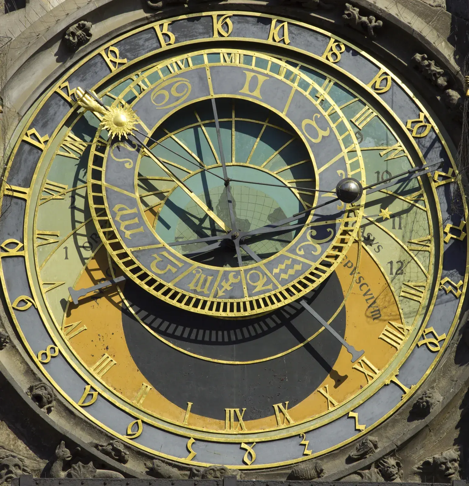 Gilded astronomical clock dial with an off-centre ring of zodiac glyphs, a sun pointer, a moon ball and a dark night zone