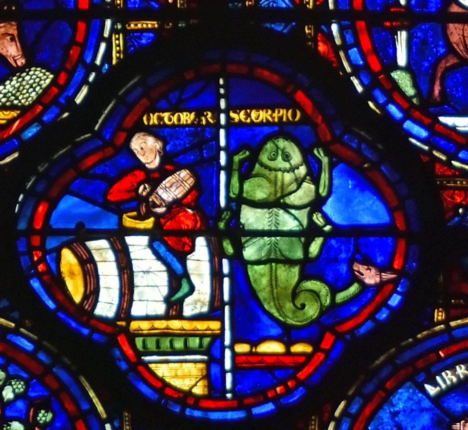 Stained-glass quatrefoil: a man in red pouring wine into a barrel on the left, a green scorpion on the right, labelled OCTOBER and SCORPIO