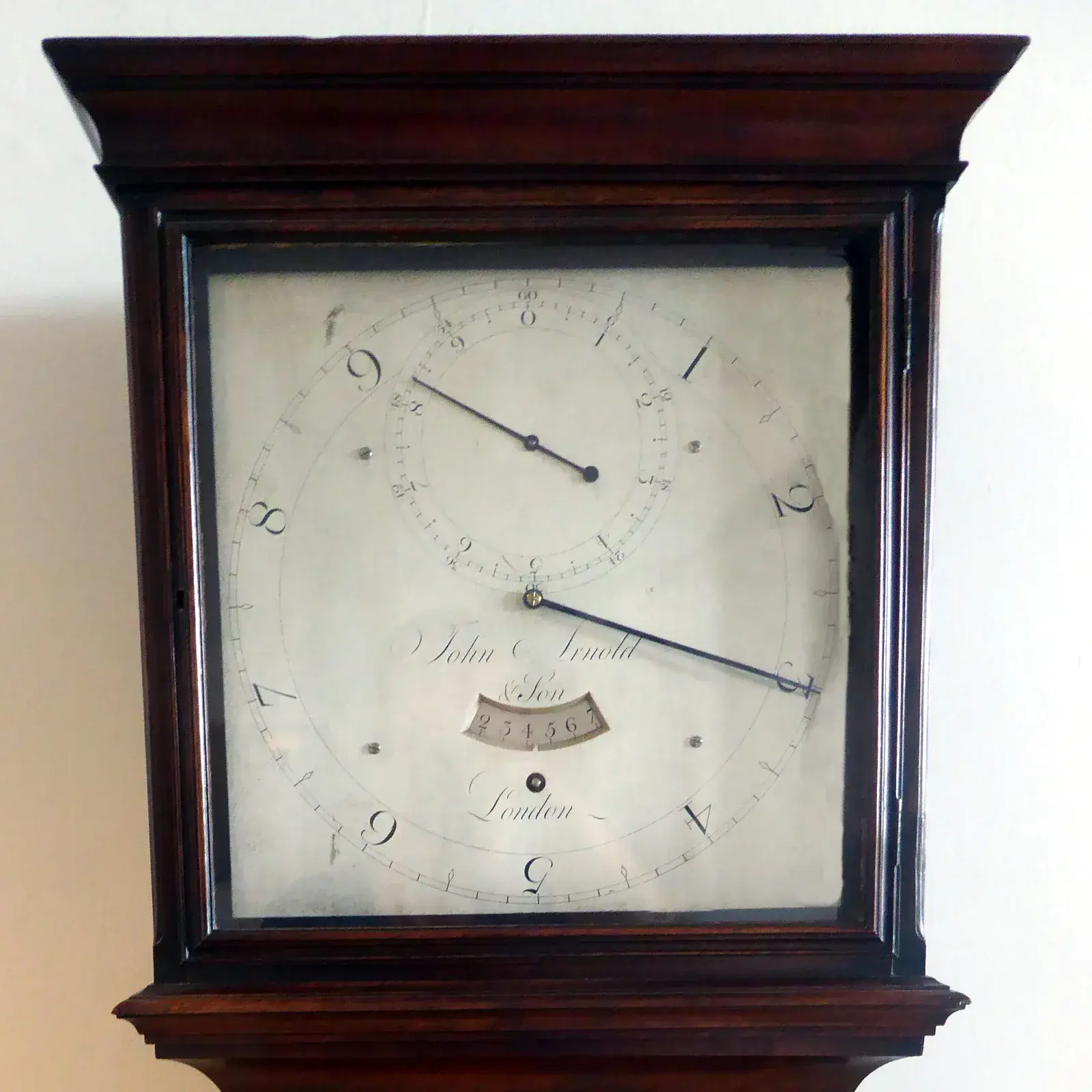 Silvered square dial of a mahogany longcase clock signed John Arnold & Son London, with a large outer ring and a subsidiary dial