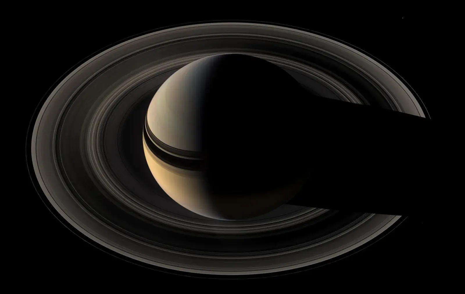 Natural colour mosaic of Saturn and its rings seen from above the rings, the planet partly in shadow against black space