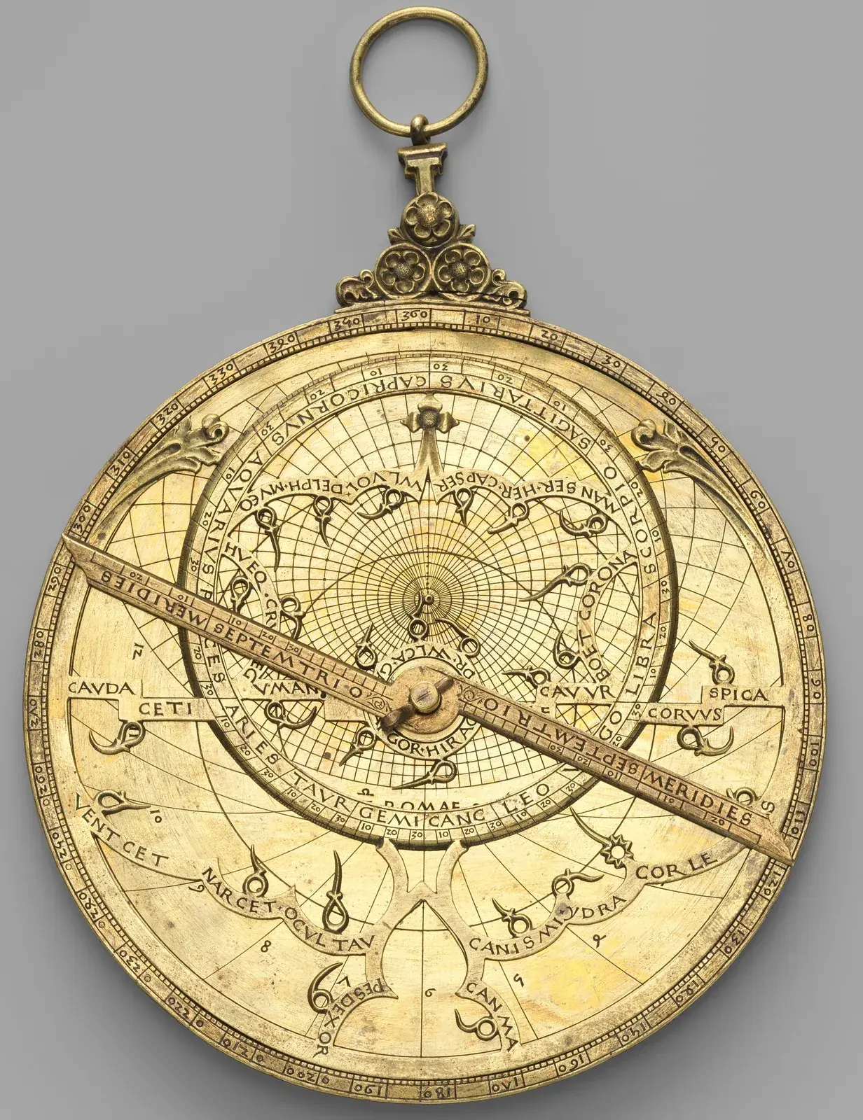 Brass astrolabe with a pierced star map on the front; its offset ring is engraved with the zodiac sign names in Latin