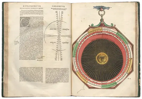 Open 1540 astronomy book with a hand-coloured paper volvelle