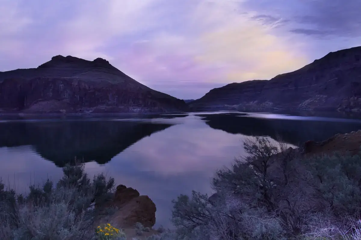 Lavender dusk sky and mountains mirrored in a still lake (Sagittarius and Capricorn compatibility)