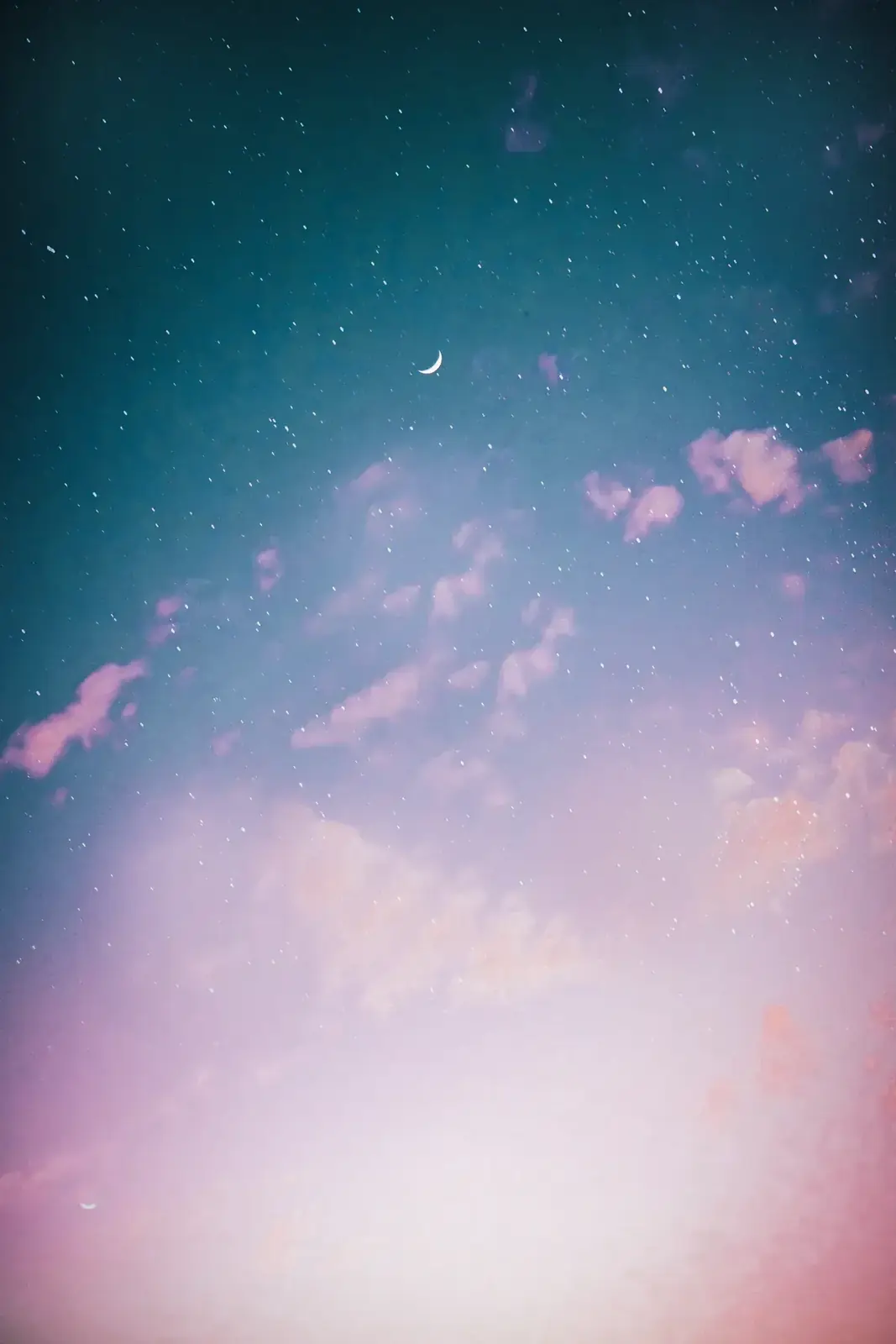 Pink clouds drifting under a starry teal sky
