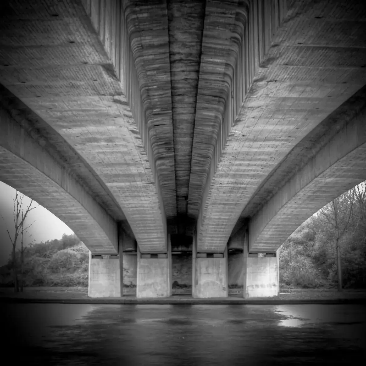 The concrete underside of a bridge stretches into the distance, in black and white (Capricorn and Aquarius compatibility)