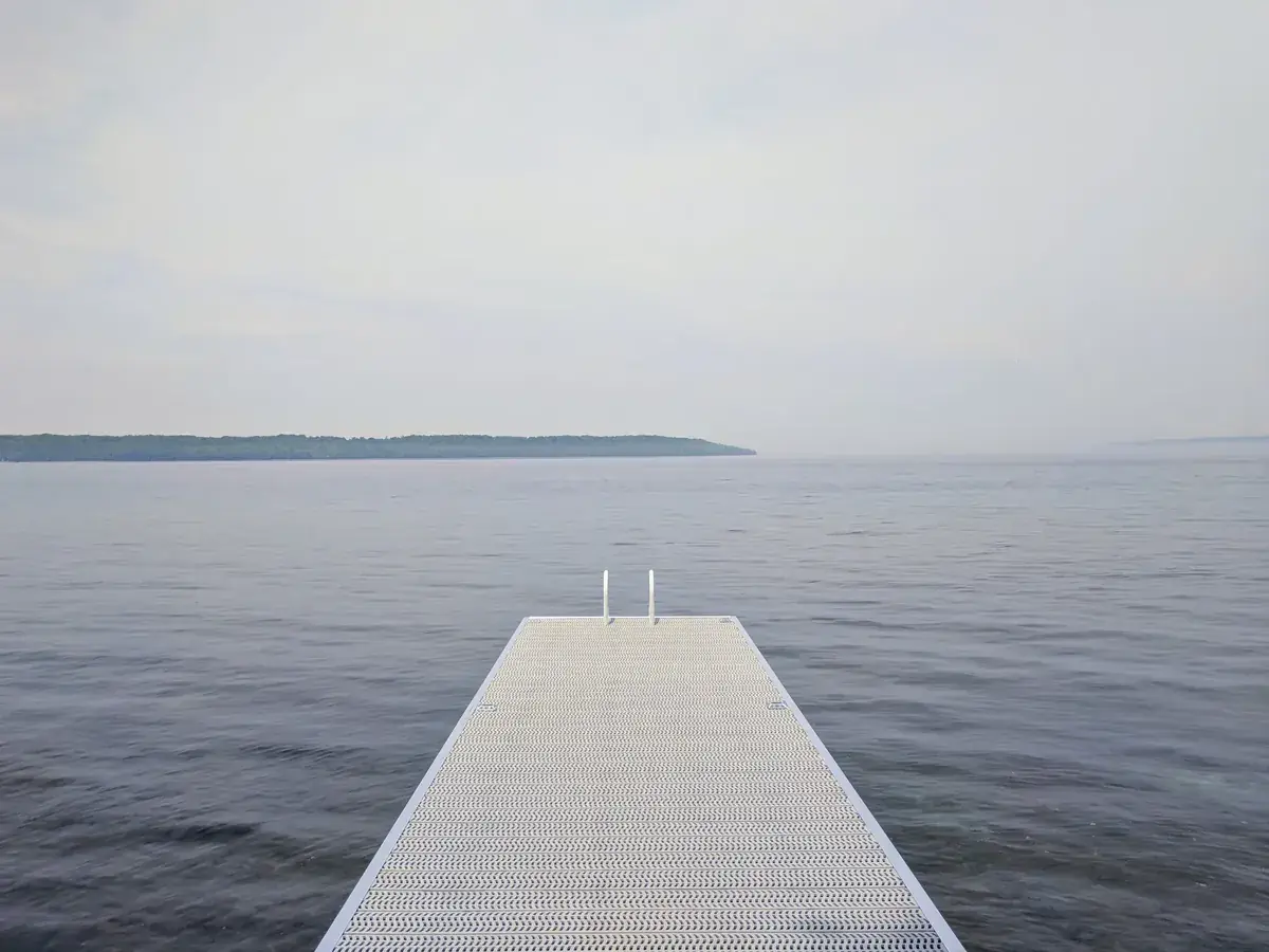 A white floating dock leads out into a calm grey lake (Cancer with Cancer compatibility)