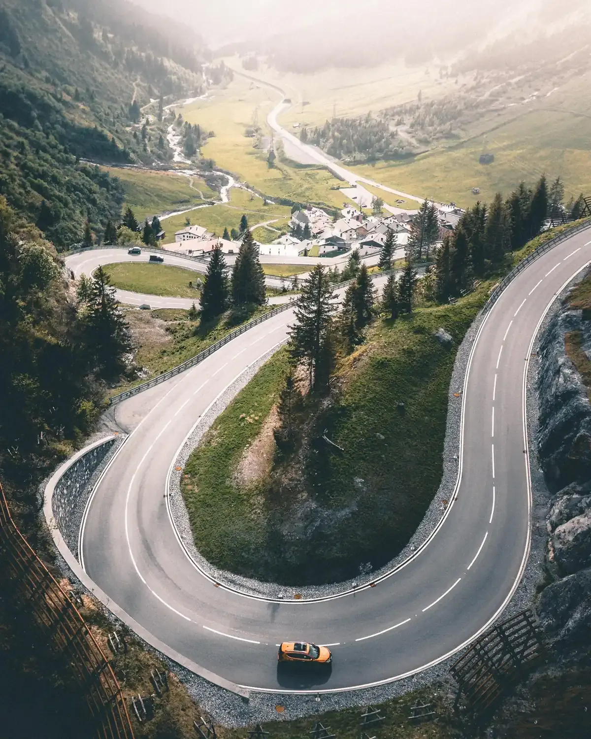 A car climbs a winding hairpin road up a mountain valley (Sagittarius with Sagittarius compatibility)