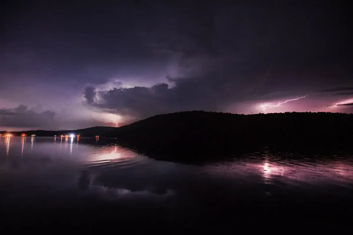 Lightning flickers over a dark lake at night, the forks reflected in the water (Aries and Scorpio compatibility)