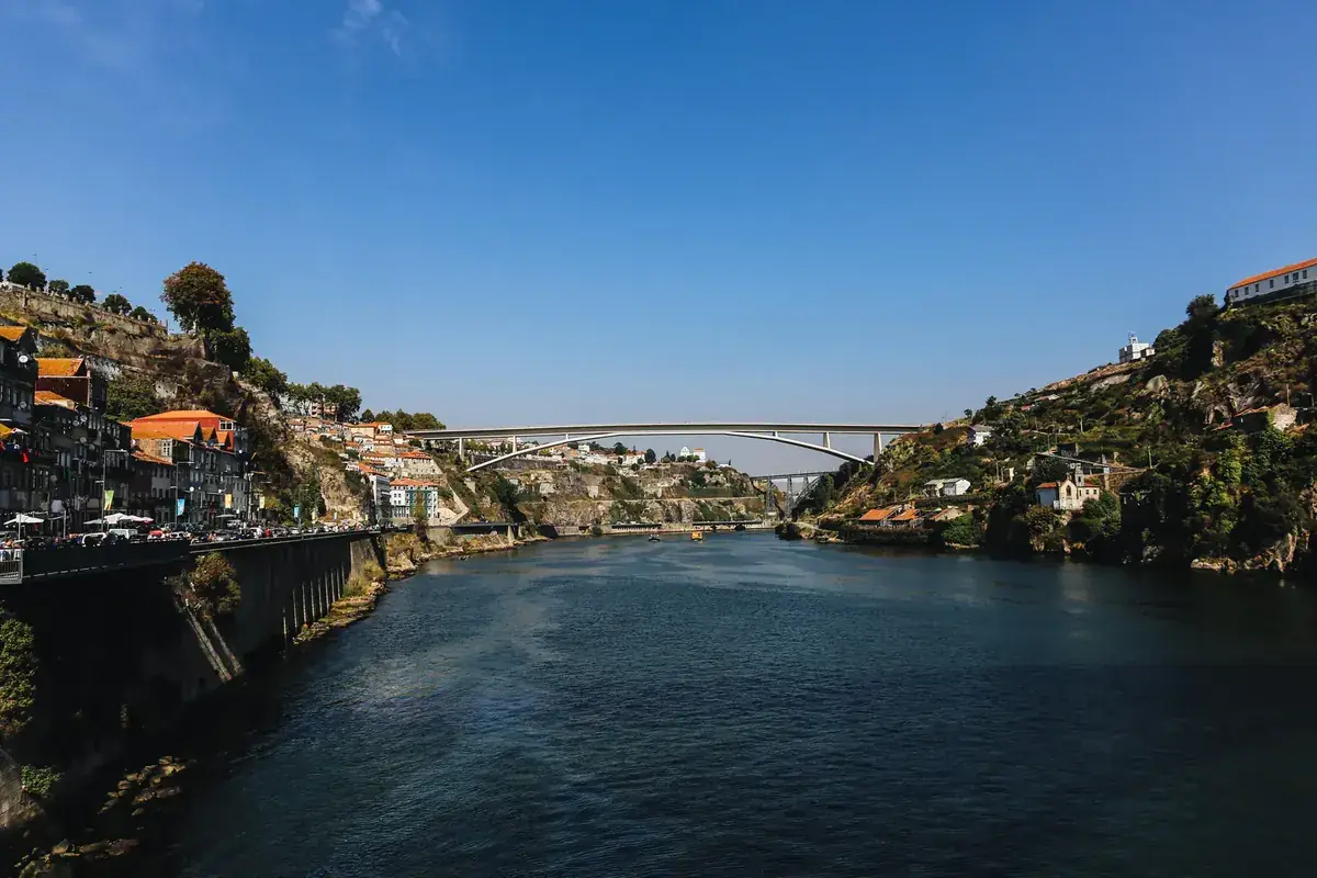 A single bridge spans a deep river gorge between two steep, sunlit banks (Aries and Libra compatibility)