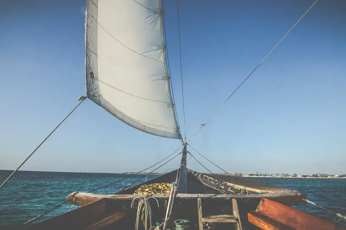A white sail fills with wind on a boat heading out to open sea (Libra and Sagittarius compatibility)