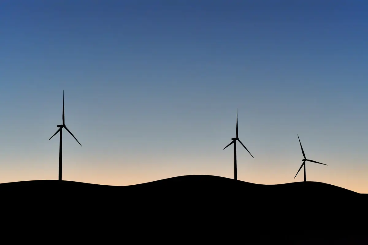 A row of wind turbines silhouetted on a ridge against a twilight sky (Aquarius with Aquarius compatibility)
