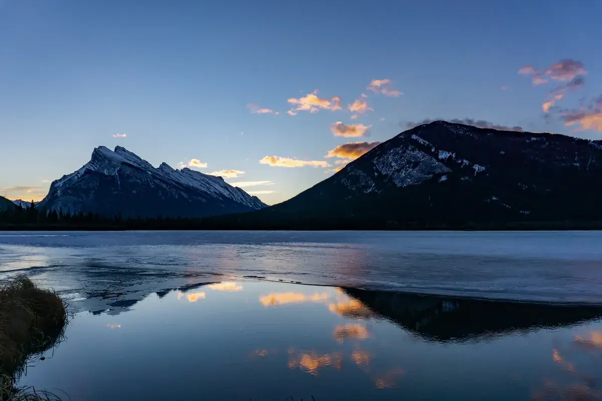 Snow-dusted mountains mirrored perfectly in a still lake at dusk (Taurus and Scorpio compatibility)